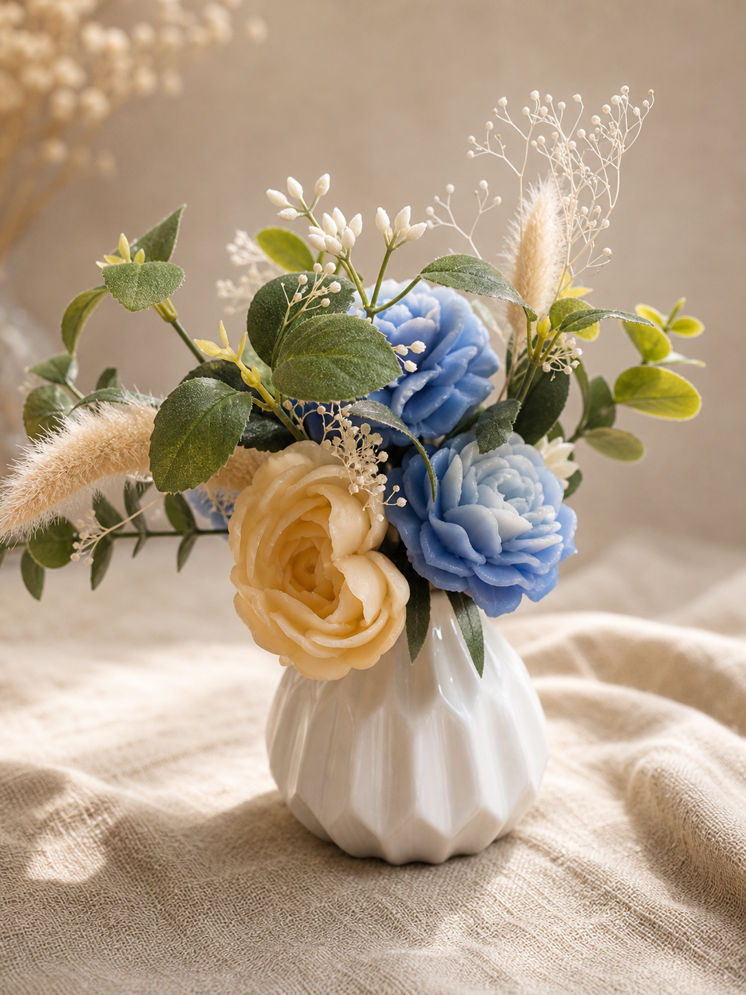 Blue and cream scented wax rose arrangement with baby's breath in a white fluted vase